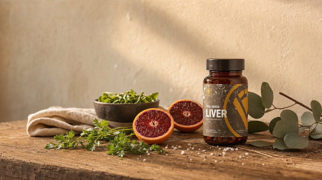Grass-fed beef liver supplement tin on weathered Australian farmhouse timber bench with fresh blood orange, parsley, leafy greens and sea salt in warm morning light