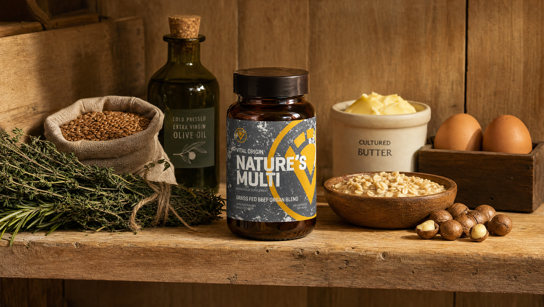 Nature's Multi beef organ supplement tin on a warm farmhouse pantry shelf with olive oil, oats, cultured butter, brown eggs, macadamias and dried herbs.